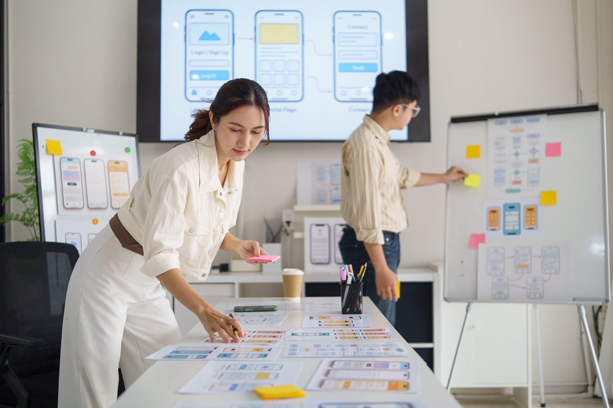 Designer sketching interface ideas on sticky notes while planning a website layout